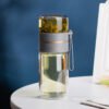 The Glass Tea Bottle next to a hot beverage, emphasizing its heat-resistant design and functionality.