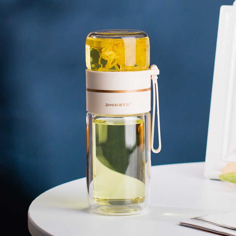 The Glass Tea Bottle with loose-leaf tea in the built-in stainless steel infuser, emphasizing its brewing functionality.